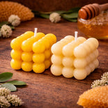 Beeswax candles shaped like honeycomb, natural honeycomb pieces, and honey dipper on rustic wood