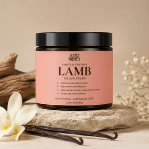 A jar of Secret Honey Limited Edition Lamb Tallow Cream sits on a stone slab with vanilla beans and dried flowers in a warm, neutral setting.